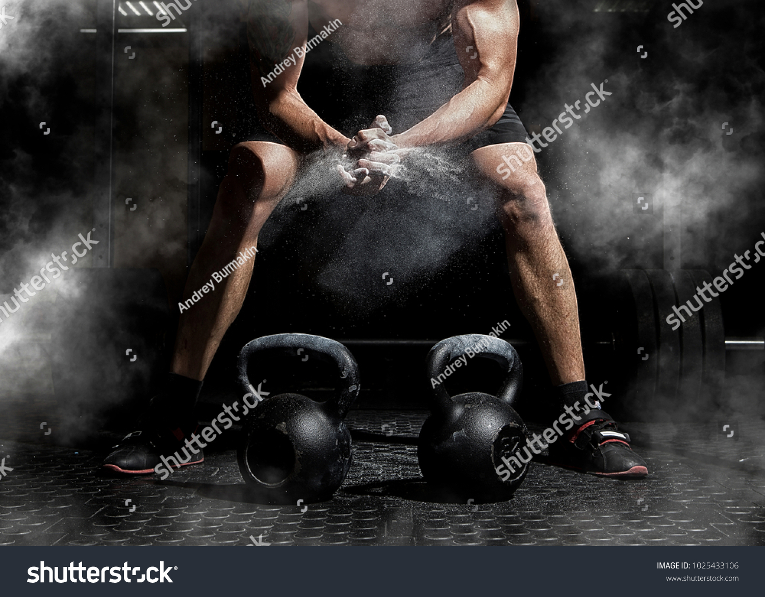 Weightlifter clapping hands and preparing for workout at a gym. Focus on dust #1025433106