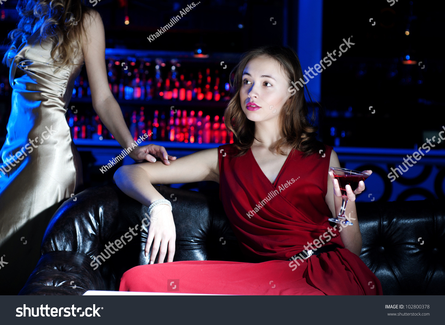 young woman has a rest with an alcoholic drink, second woman on a background #102800378