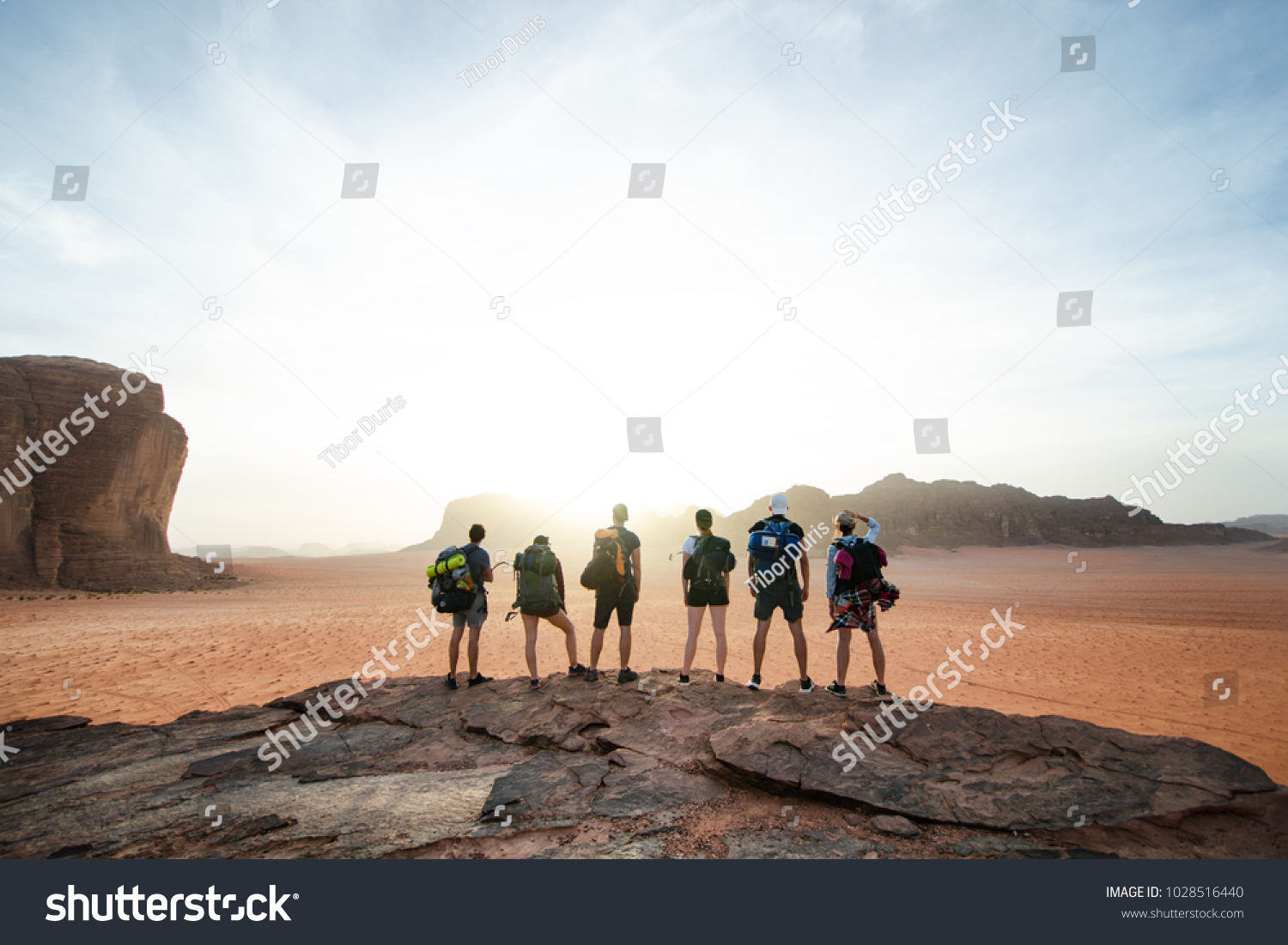 Tourist friends on a top of mountains in a desert. Sunset view. Nature. Tourist people enjoy a moment in a nature. Wadi rum national park - Jordan  #1028516440