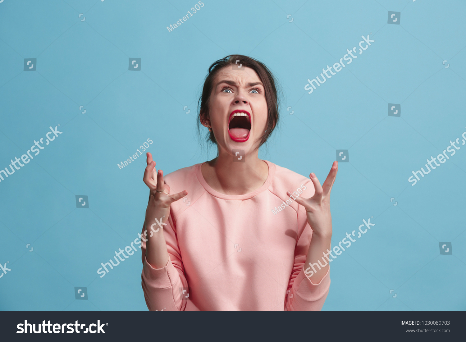 Screaming, hate, rage. Crying emotional angry woman screaming on blue studio background. Emotional, young face. Female half-length portrait. Human emotions, facial expression concept. Trendy colors #1030089703