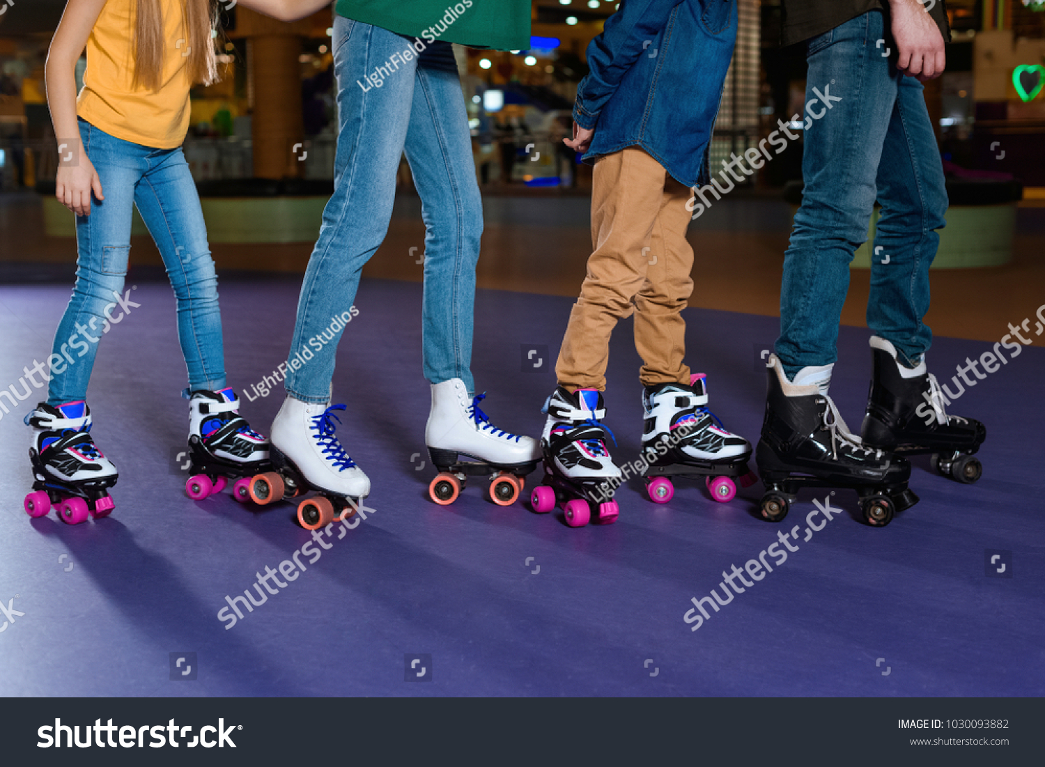 partial view of parents and kids skating on roller rink together #1030093882