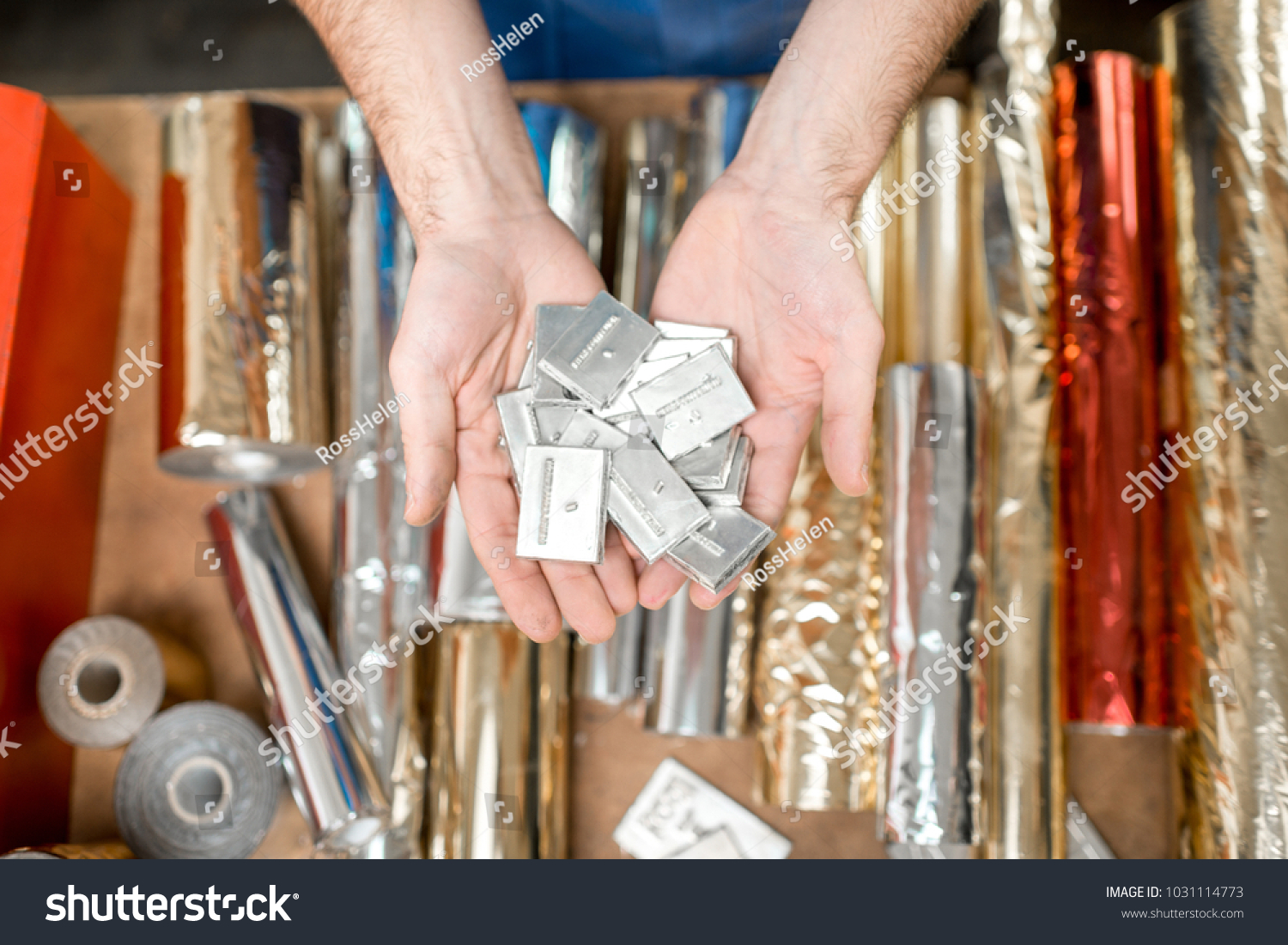 Holding a pile of small metal cliche for stamping with foil at the printing manufacturing #1031114773