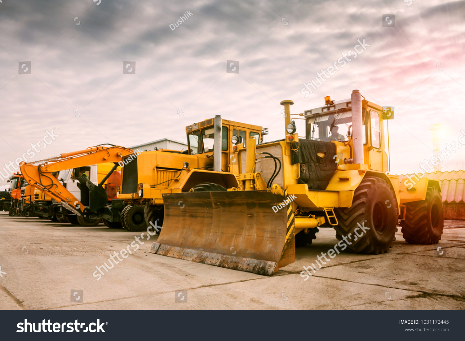 Dva těžký kolový traktor jeden rypadlo a další stavební stroje na ranním slunci #1031172445