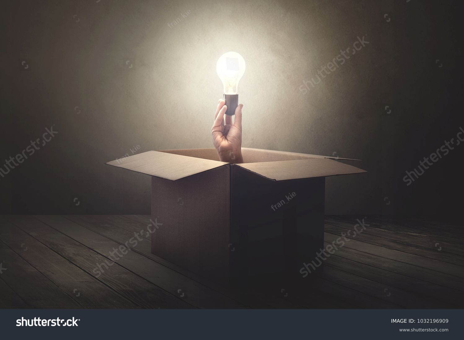 hand holding light bulb coming out from a paper box #1032196909