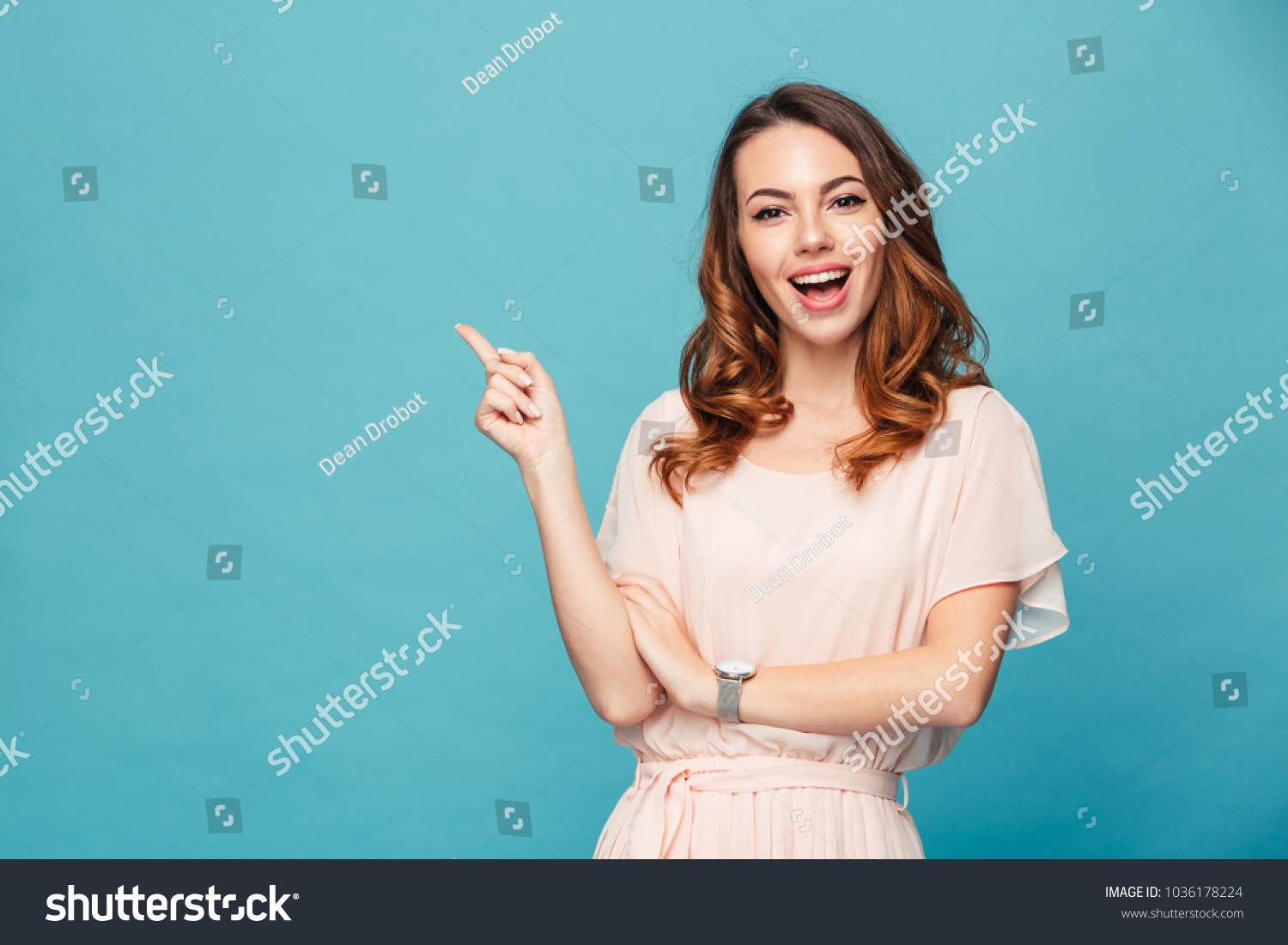 Image of happy young lady standing isolated over blue background. Looking camera pointing. #1036178224