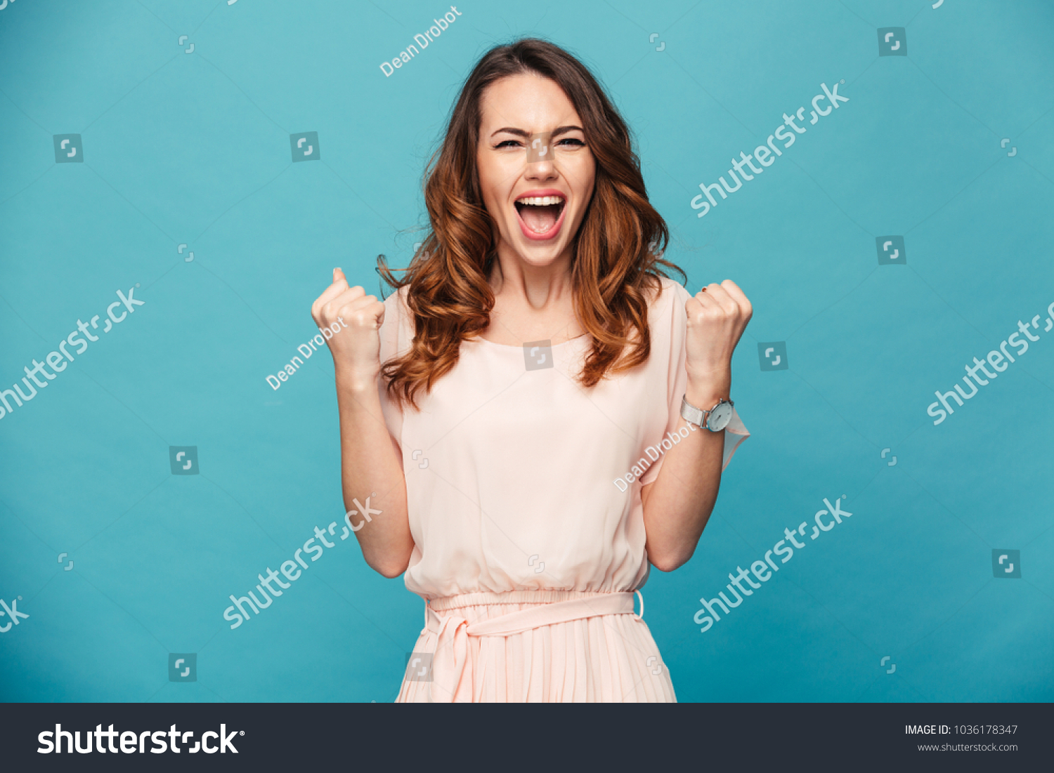 Image of excited young lady standing isolated over blue background make winner gesture. #1036178347