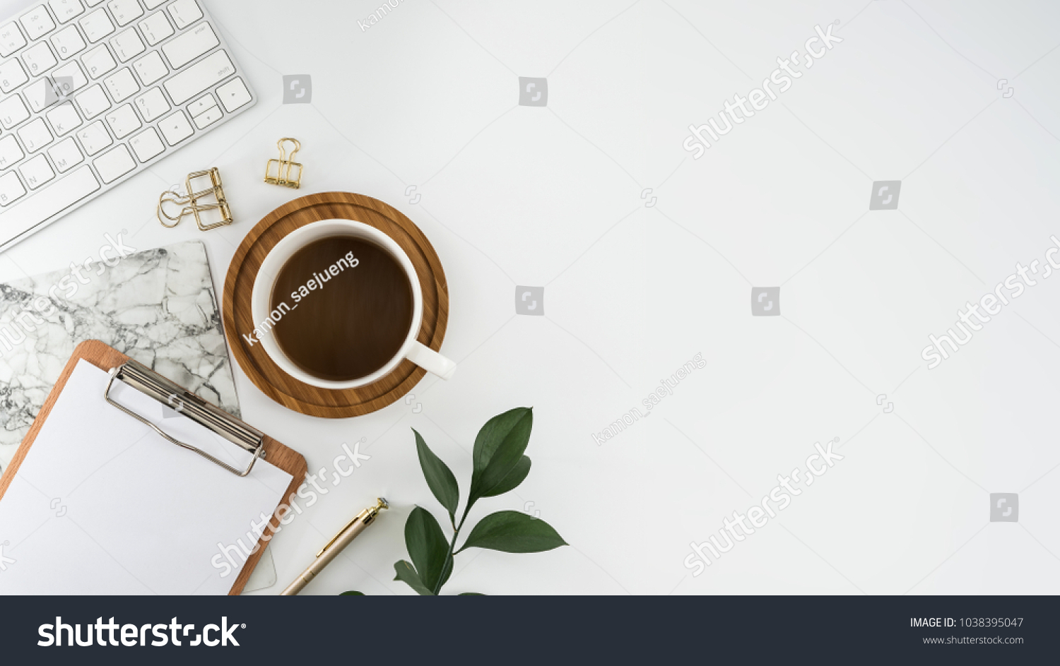 Flat lay, top view office table desk. Workspace with blank clip board, keyboard, office supplies, pencil, green leaf, and coffee cup on white background. #1038395047