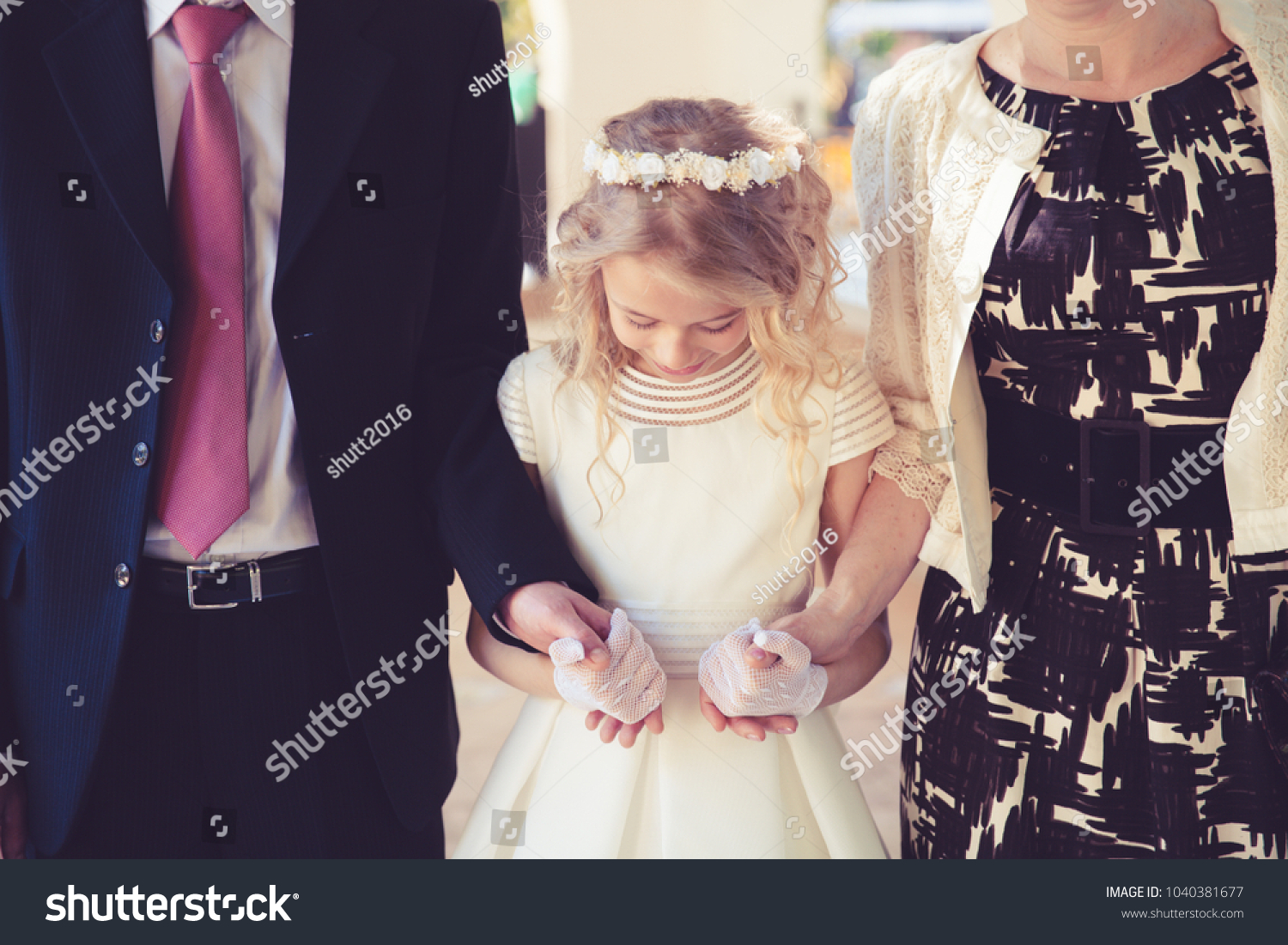 Little Girl in her First Communion Day with Her Father and mother. #1040381677