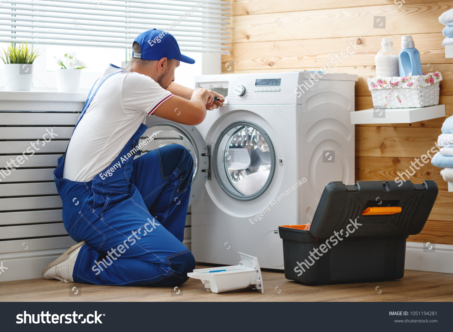 working man plumber repairs a washing machine in   laundry #1051194281