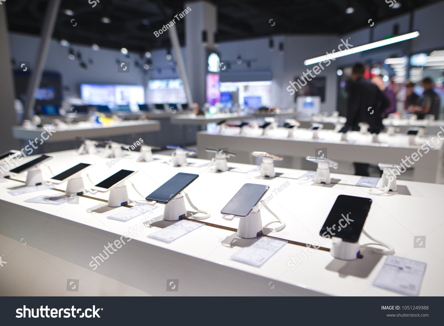Showcase with smartphones in the modern electronics store. Buy a mobile phone. Many smartphones on the shelf of the technology store #1051249988