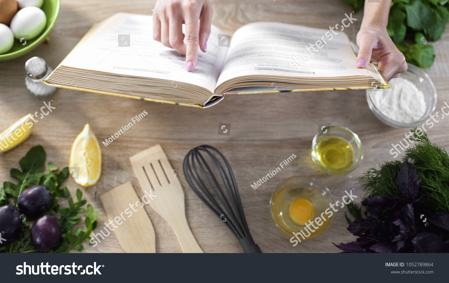 Lady reading pizza recipe in culinary book at home with kitchenware on table #1052789864