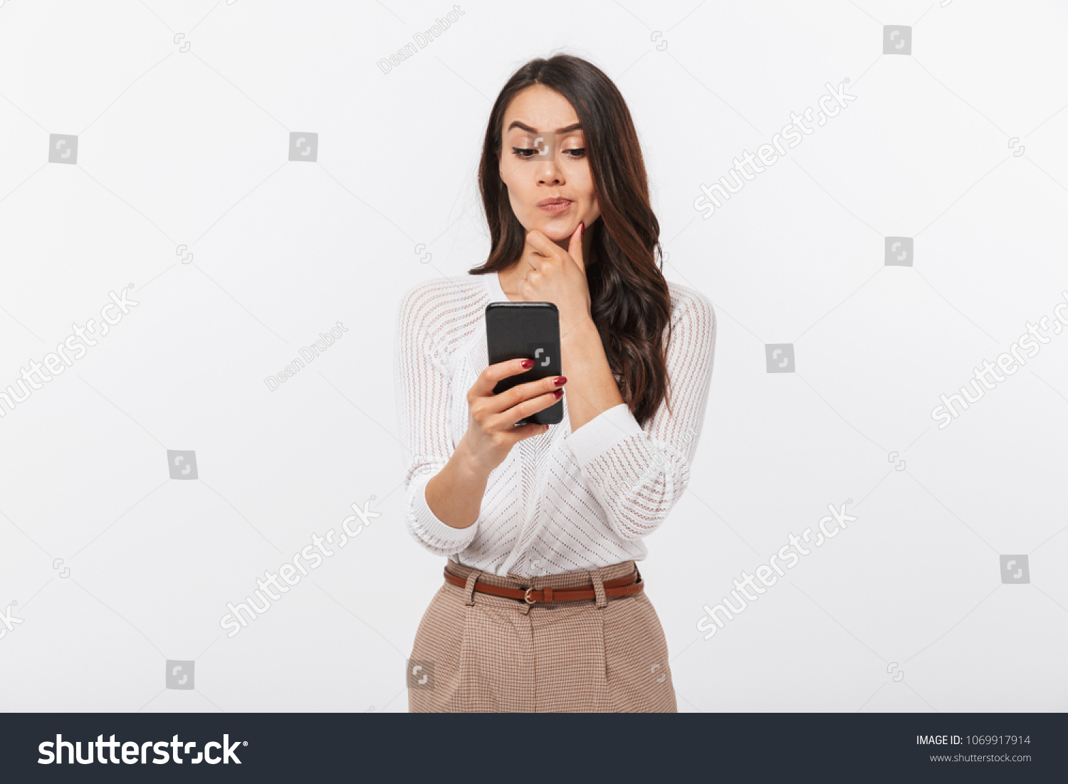 Portrait of a pensive asian businesswoman using mobile phone isolated over white background #1069917914