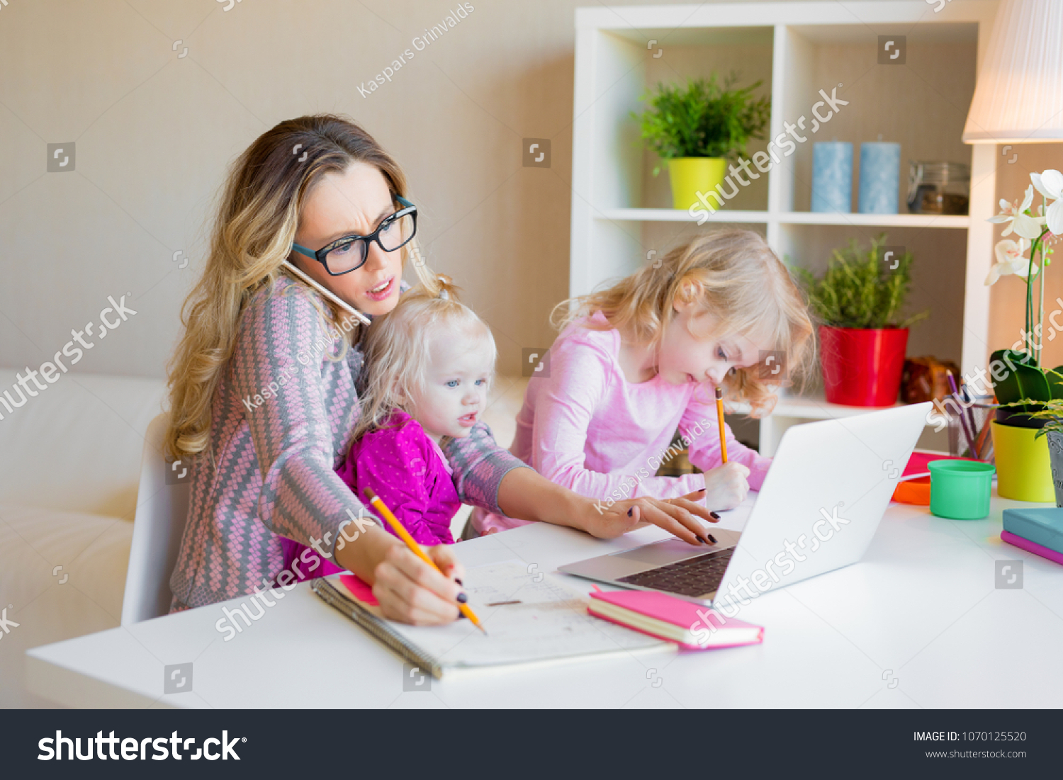 Busy woman trying to work while babysitting two kids #1070125520