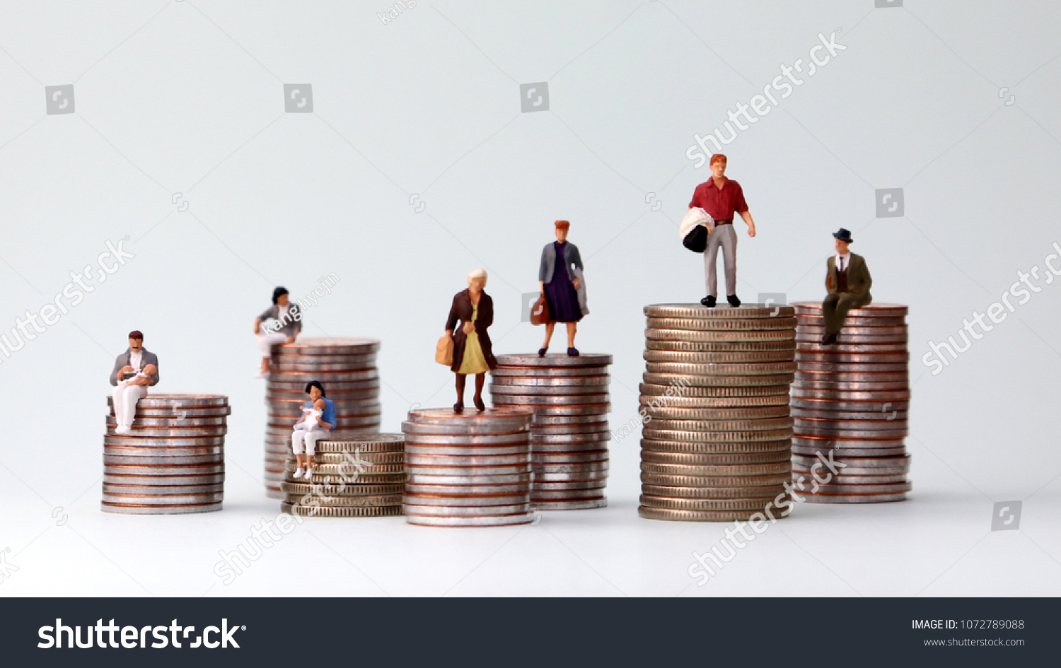 Miniature people standing on piles of different heights of coins. Income and economic inequality concept. #1072789088