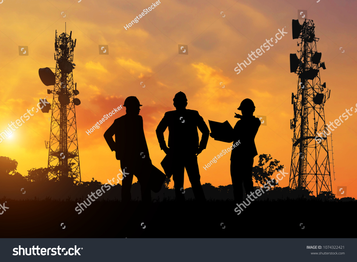 Silhouette of the engineers look at the telecommunication poles planned to be built at sunset time. #1074322421