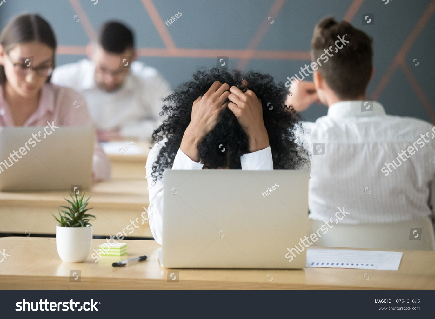 Frustrated african woman feeling despair panic shock sitting in shared office with laptop holding head in hands, upset stressed black employee or student tired of work, worried about online problem #1075401695