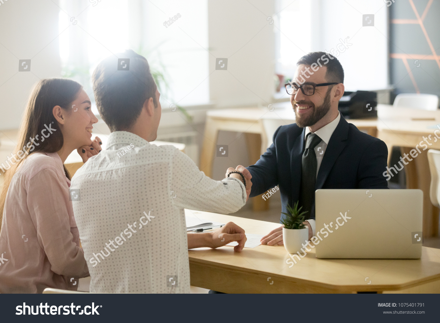 Smiling lawyer, realtor or financial advisor handshaking young couple thanking for advice, insurance broker or bank worker and millennial customers shake hands making deal, investment or taking loan #1075401791