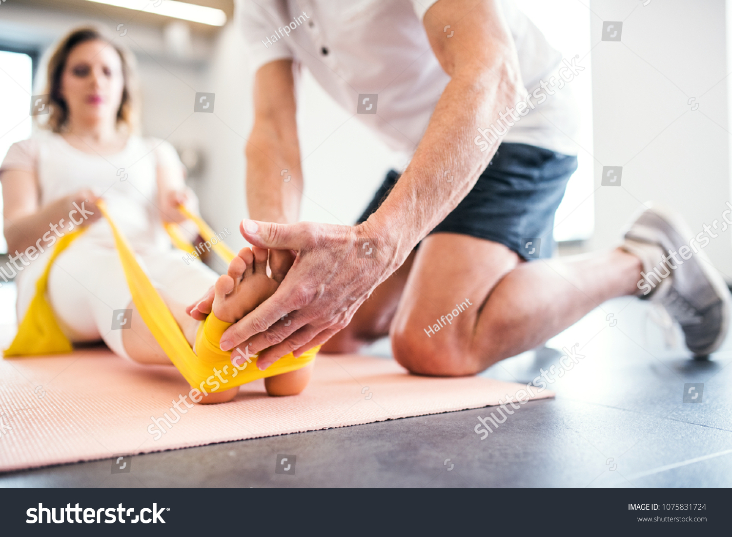 Unrecognizable senior physiotherapist working with a female patient. #1075831724