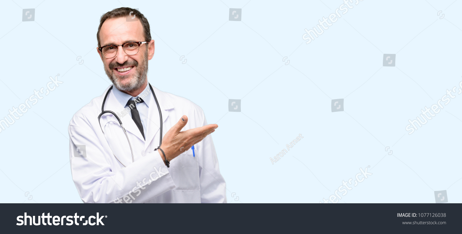 Doctor senior man, medical professional holding something in empty hand isolated over blue background #1077126038