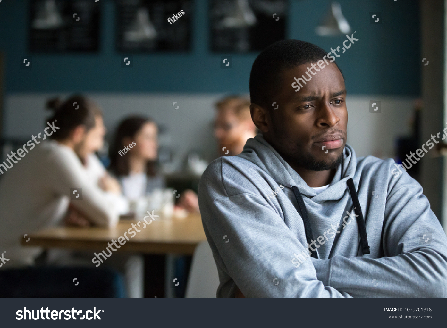 Frustrated excluded outstand african american man suffers from bullying or racial discrimination having no friends sitting alone in cafe, sad depressed black guy upset being rejected by white people #1079701316