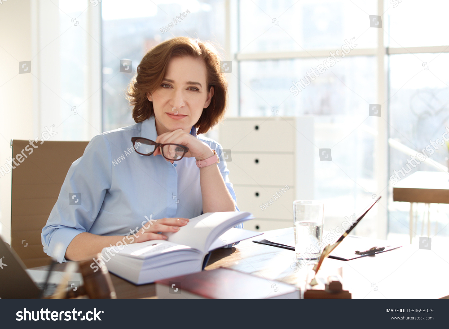Female lawyer working at table in office #1084698029
