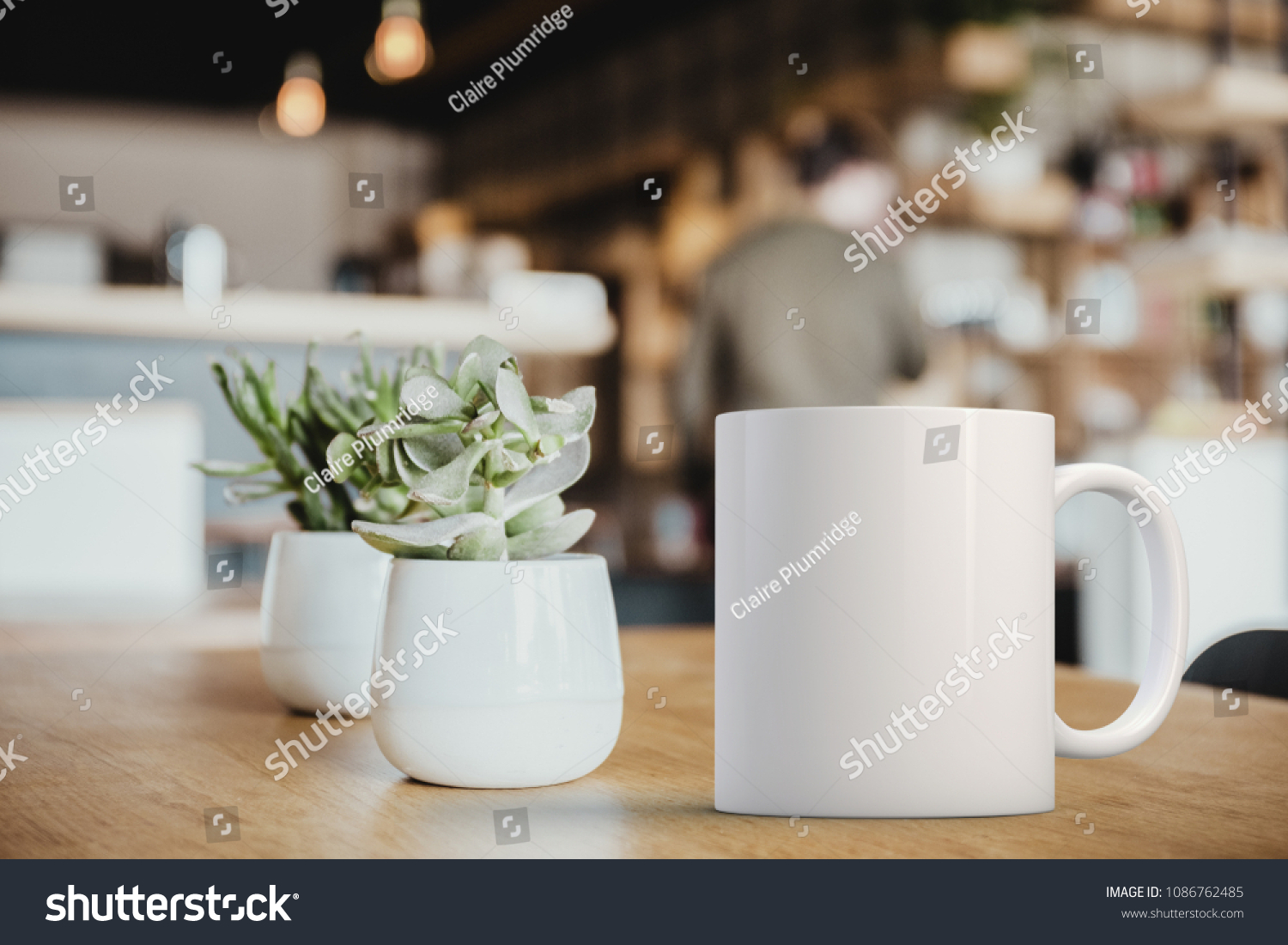 White coffee Mug Mockup set-up in a cafe, next to cactus plants and with blurred background. Great for overlaying your custom quotes and designs for selling mugs. #1086762485