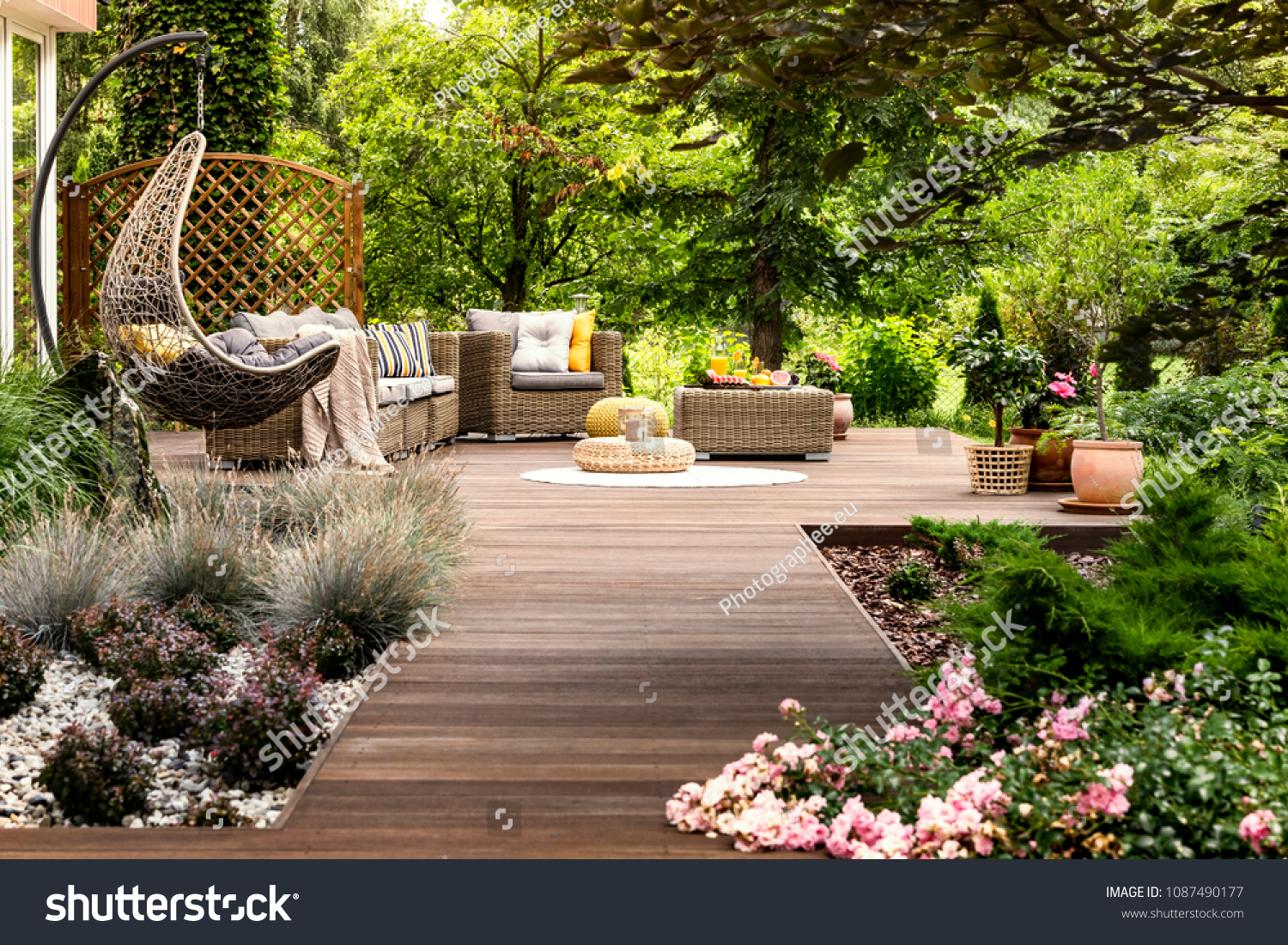 Beautiful wooden terrace with garden furniture surrounded by greenery on a warm, summer day #1087490177