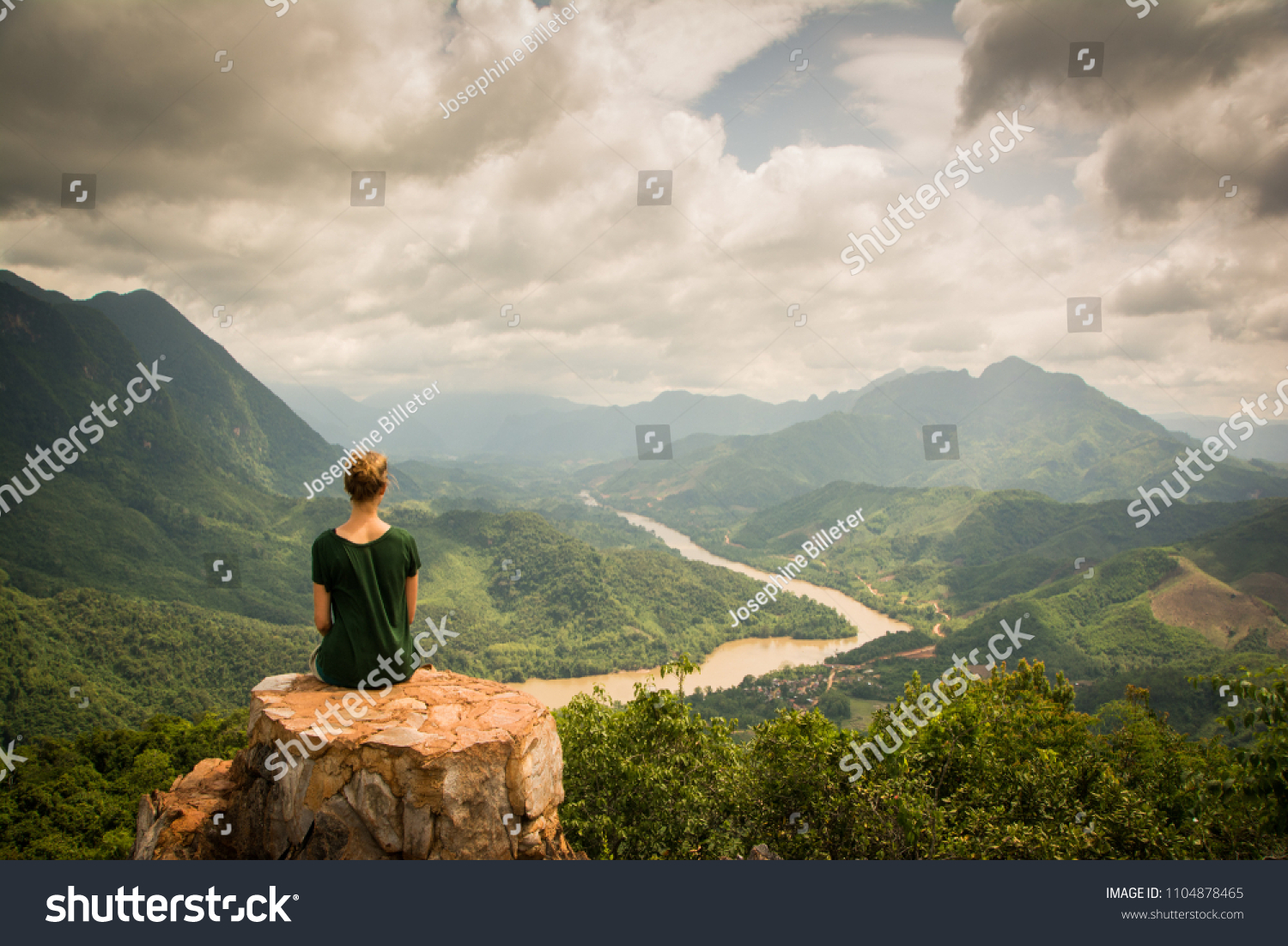 Girl with green shirt sitting on a rock on top of a mountain watching the beautiful scenery of the backcountry of Nong Khiaw, Laos. Location: Viewpoint in Nong Khiaw.  #1104878465