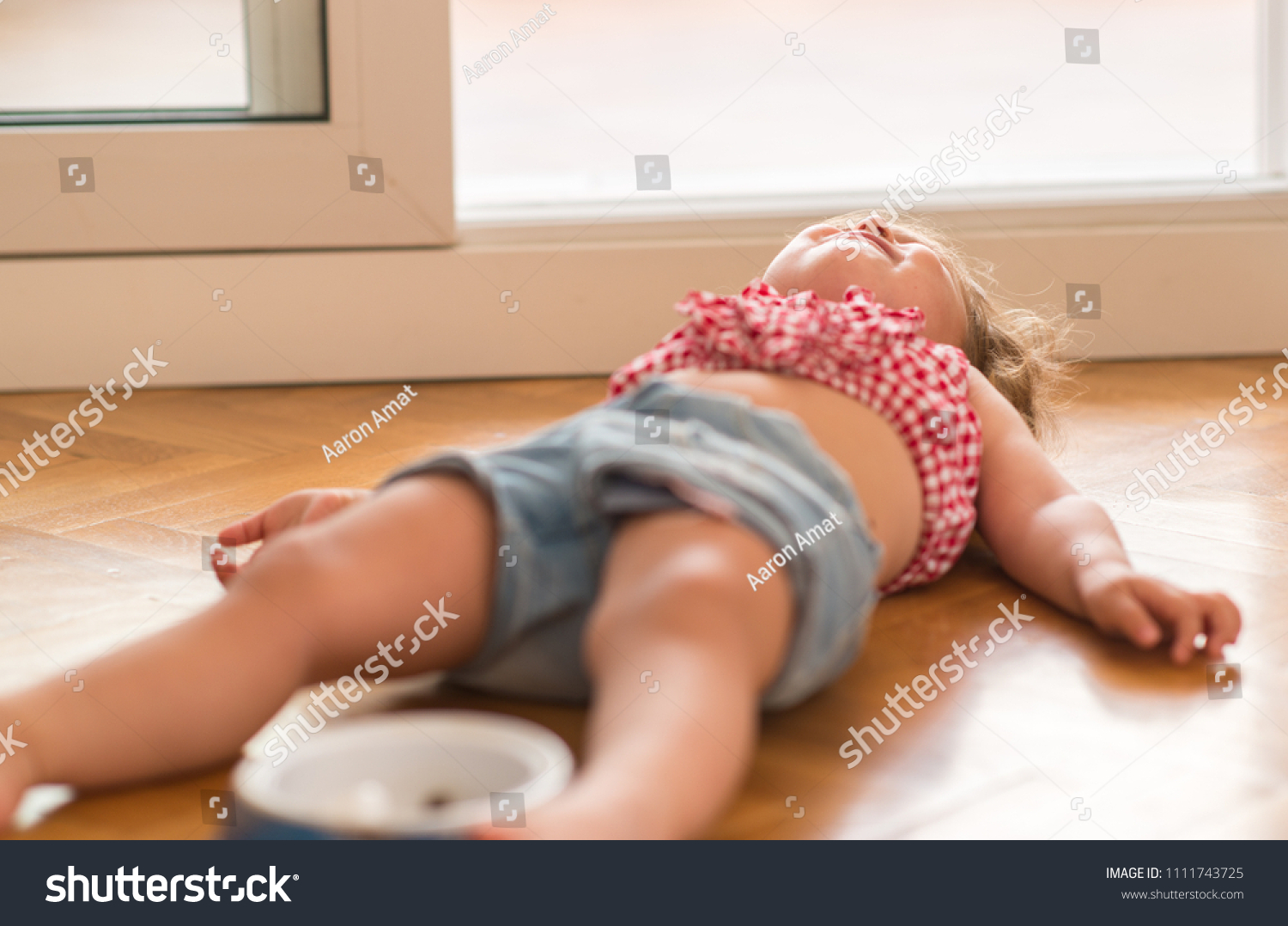 Beautiful blond child crying and shouting with tantrum laying on the floor at home. #1111743725