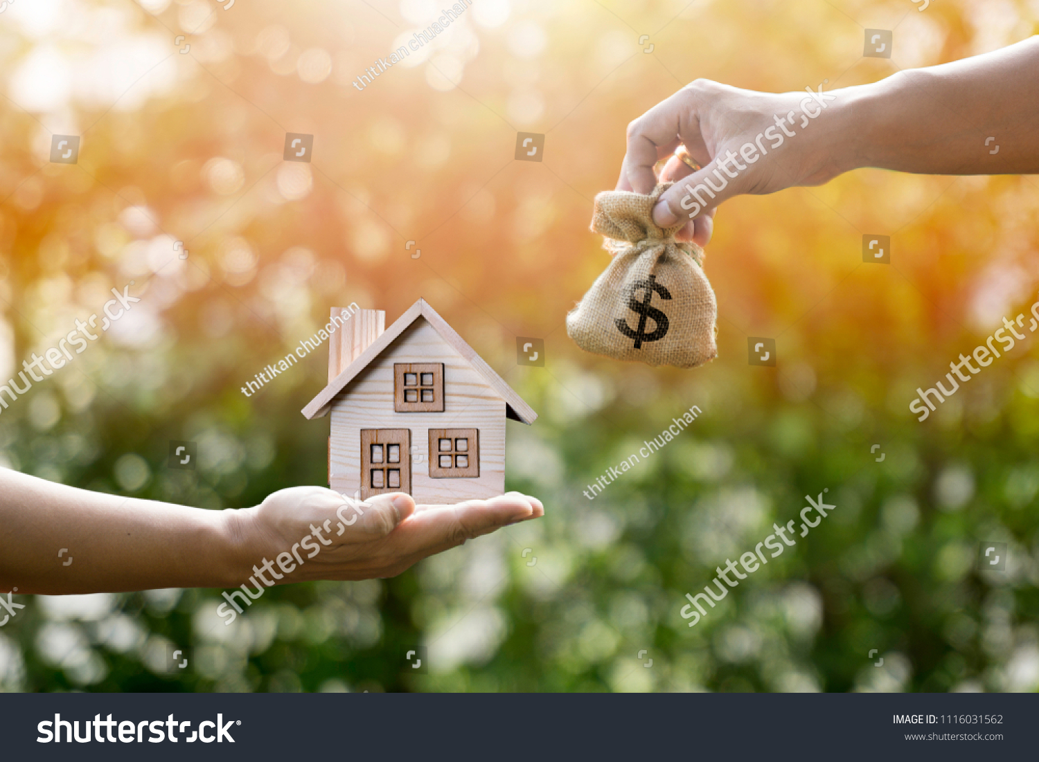 Money bag home and man hands in sunlight represent to exchange or saving money or investing to buy a home or loan to buy a house or real estate or investment for the future. #1116031562