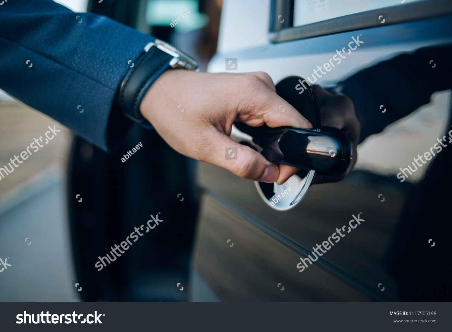 Close-Up Shot of a Professional Businessman with his Hand Firmly on the Car Door Handle, Demonstrating Elegance and Confidence while Opening the Door to his Vehicle #1117505198