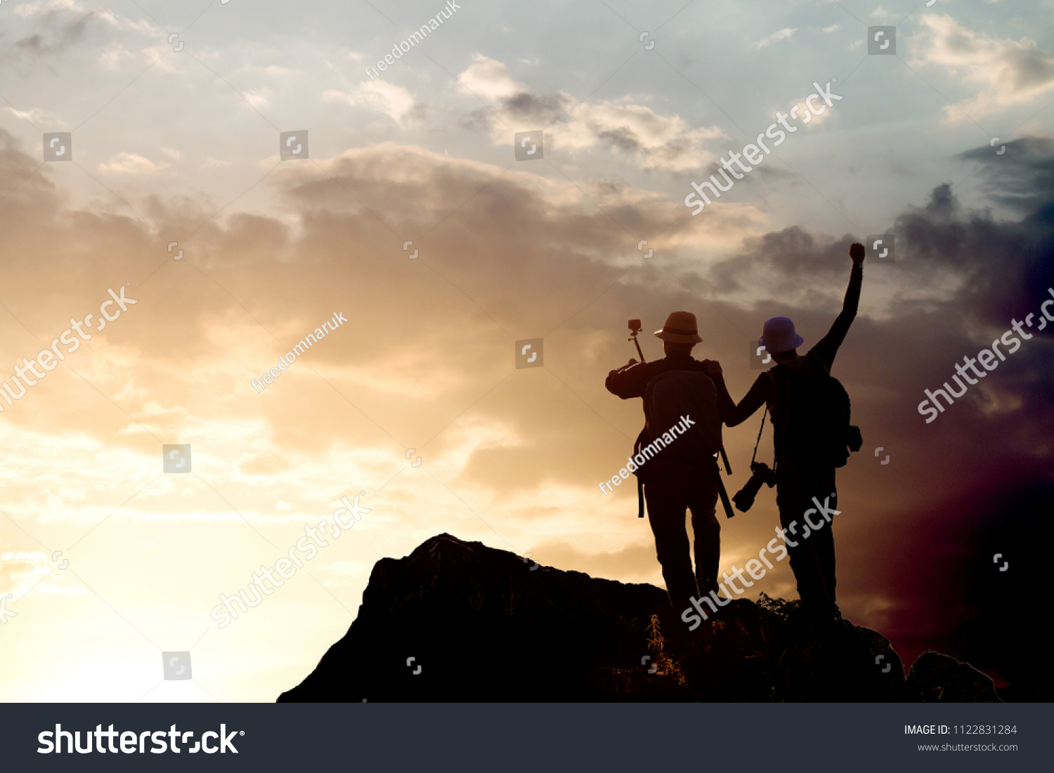 Silhouette of man hold up hands on the peak of mountain #1122831284