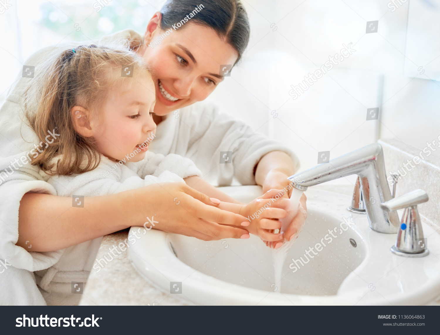 Cute little girl and her mother are washing hands under running water. #1136064863