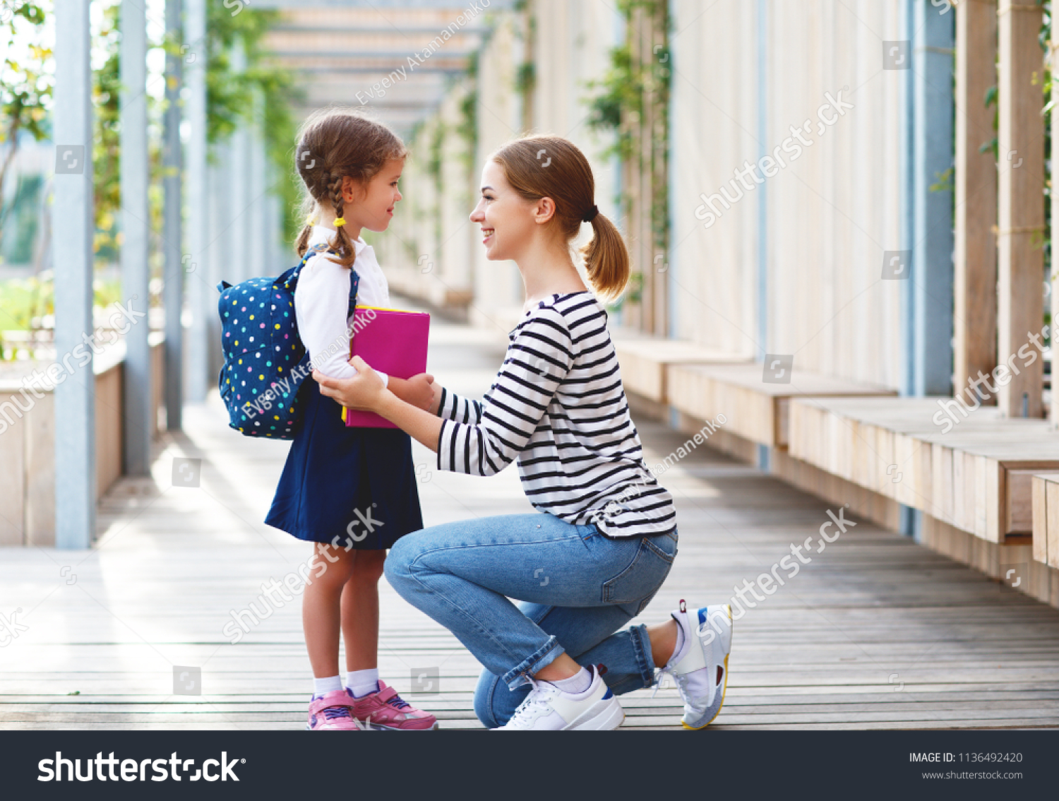 first day at school. mother leads a little child school girl in first grade #1136492420