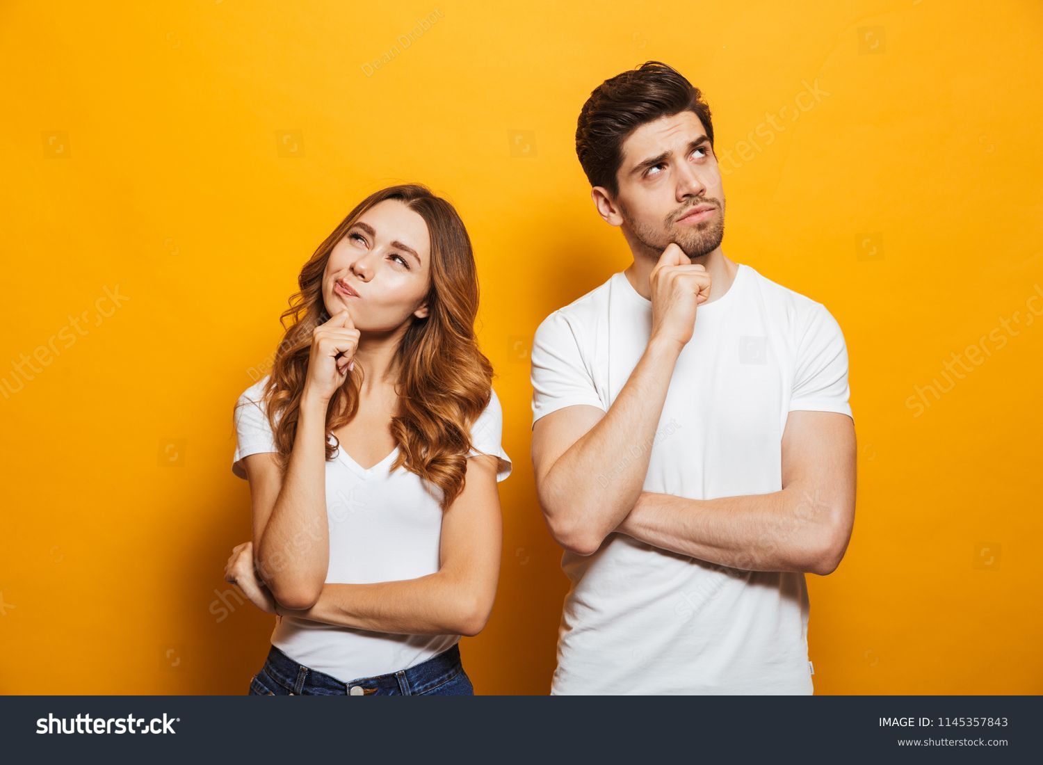 Image of happy young people man and woman in basic clothing thinking and touching chin while looking aside isolated over yellow background #1145357843