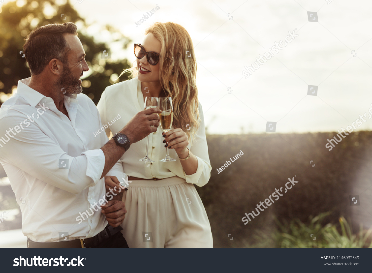 Romantic couple toasting wine glasses outdoors. Beautiful woman clinking wine glass with her boyfriend. #1146932549