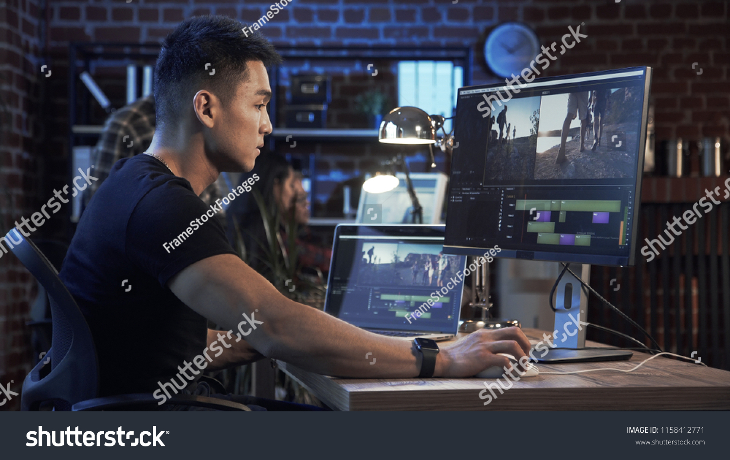 Side view of casual confident Korean man working on computer with video editing and color correction #1158412771