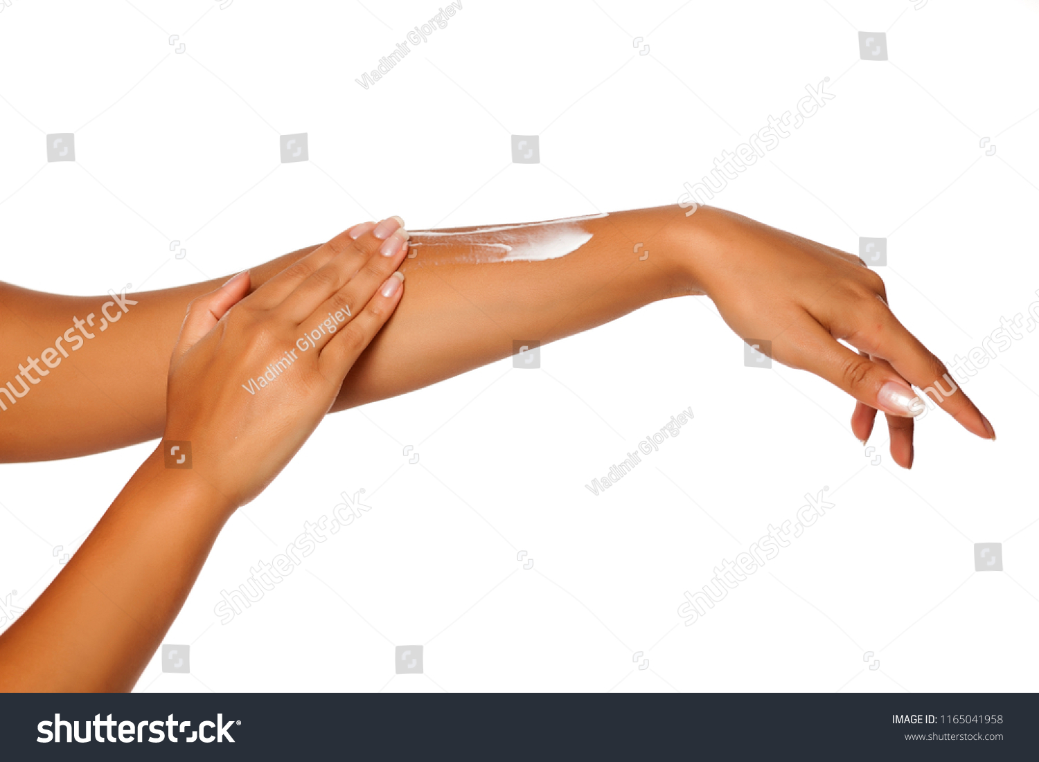 closeup of female dark skinned hands applying hand cream on white background #1165041958