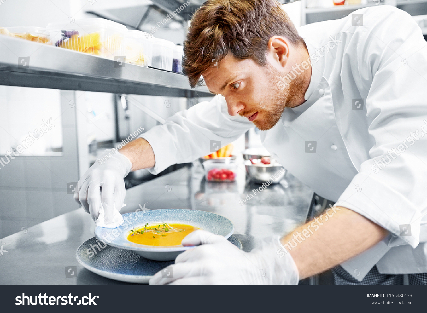 food cooking, profession and people concept - happy male chef cook serving and cleaning plate of soup at restaurant kitchen #1165480129