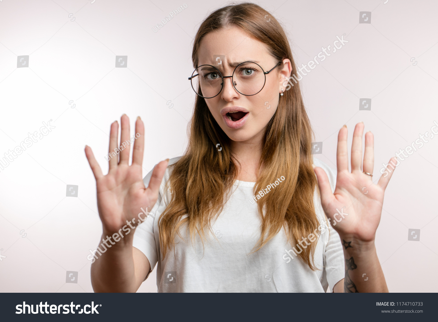 Young beautiful woman in glasses making the hand stop sign, isolated on the white background. close up photo. calm down, please. Don't worry #1174710733