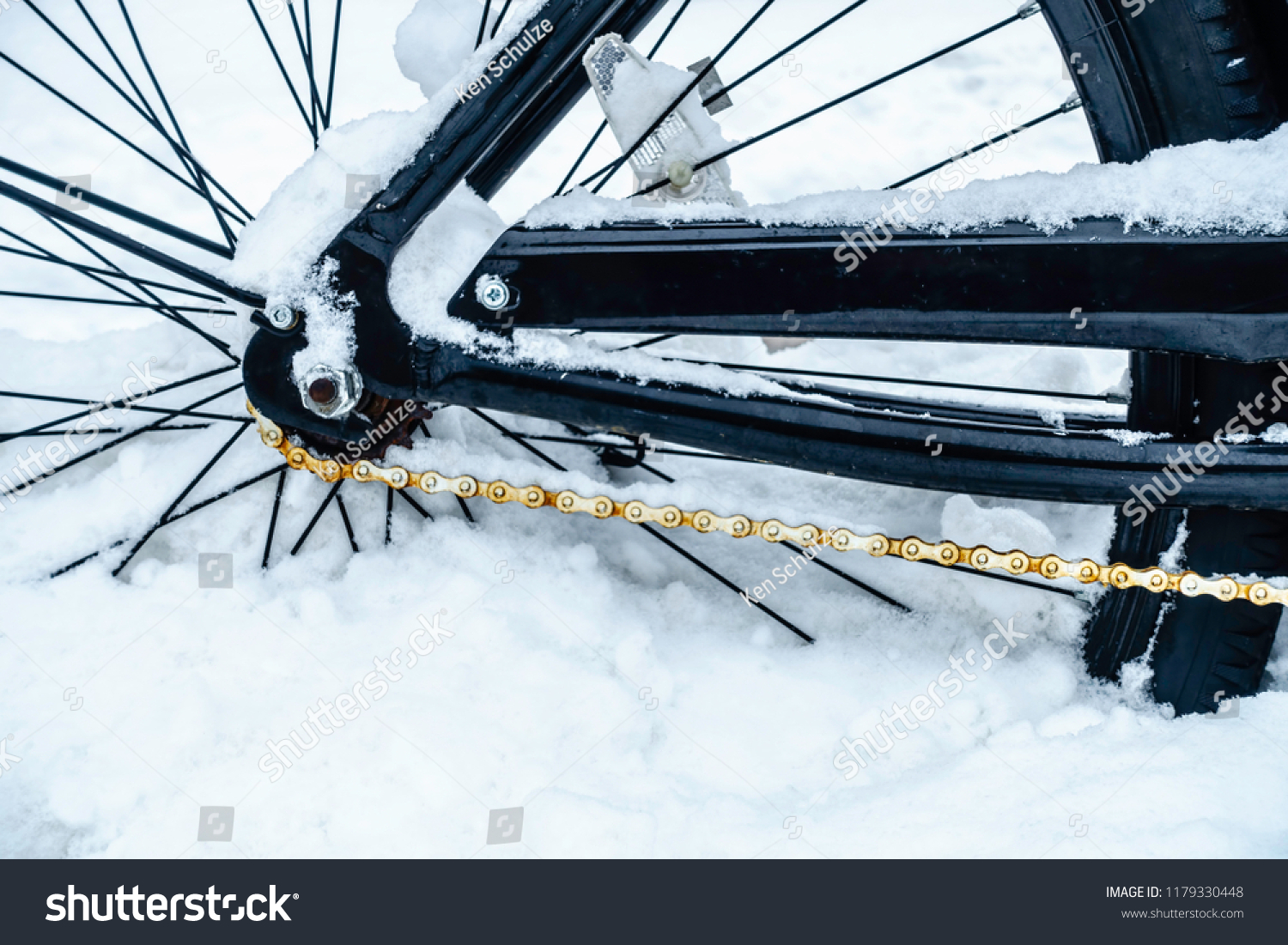 Winter at a glance: Closeup of rear wheel and rusting chain of bicycle stuck in snow, for themes of weather, transportation, adversity #1179330448