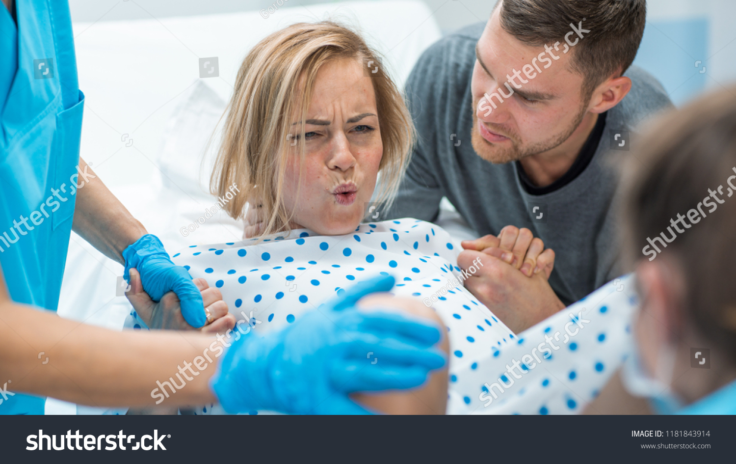 In the Hospital Woman in Labor Pushes to Give Birth, Obstetricians Assisting, Husband Holds Her Hand for Support. Modern Delivery Ward with Professional Midwives. #1181843914
