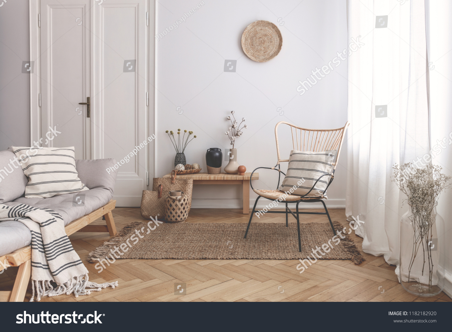 Armchair on rug next to bench with plants in white loft interior with wooden sofa. Real photo #1182182920