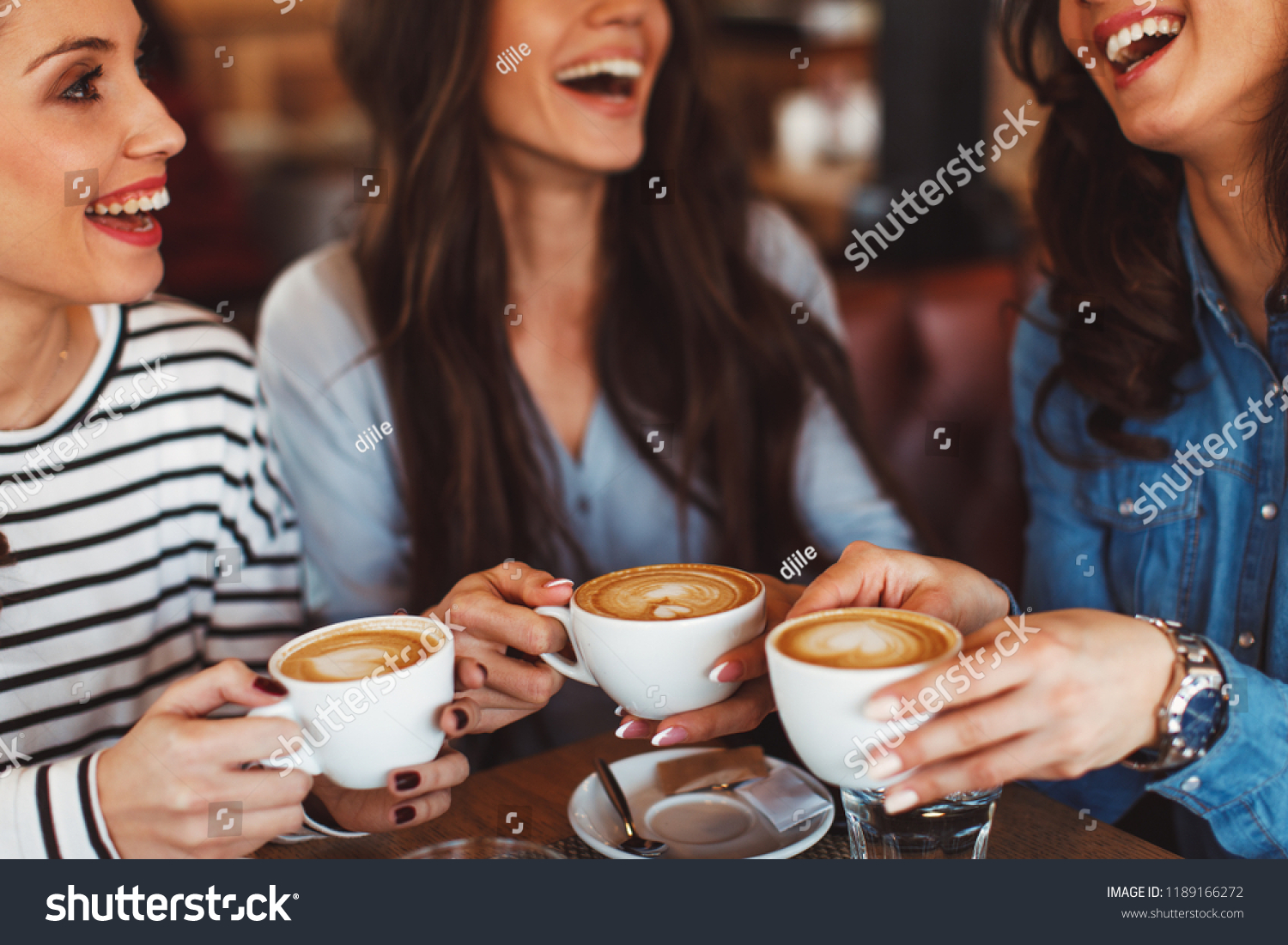 Three young women enjoy coffee at a coffee shop #1189166272