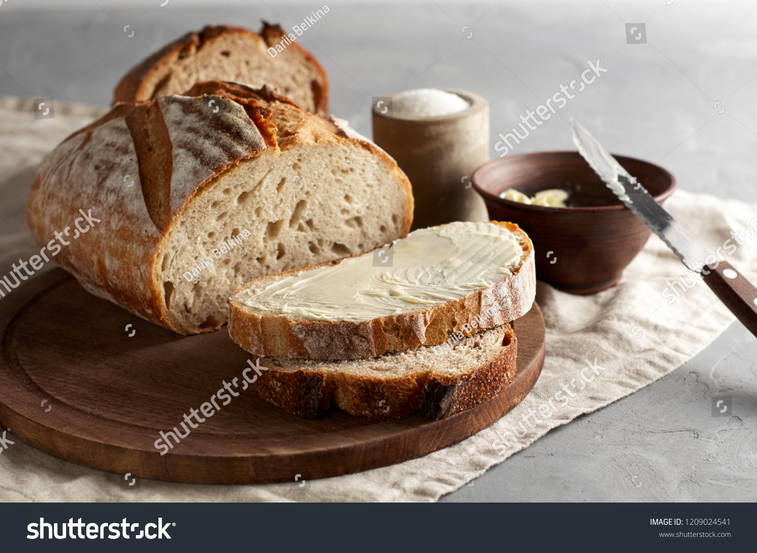 Artisan sliced toast bread with butter and sugar on wooden cutting board. Simple breakfast on grey concrete background. Closeup view #1209024541