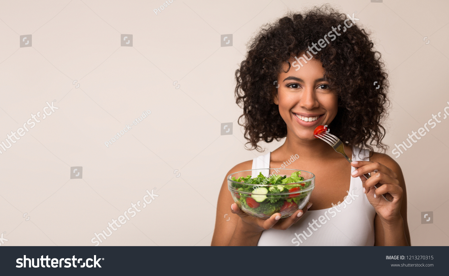 African-american woman eating vegetable salad over light background with copy space #1213270315