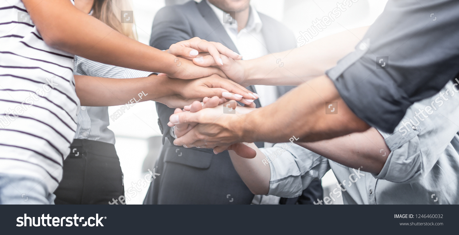 Close up view of young business people putting their hands together. Stack of hands. Unity and teamwork concept. #1246460032