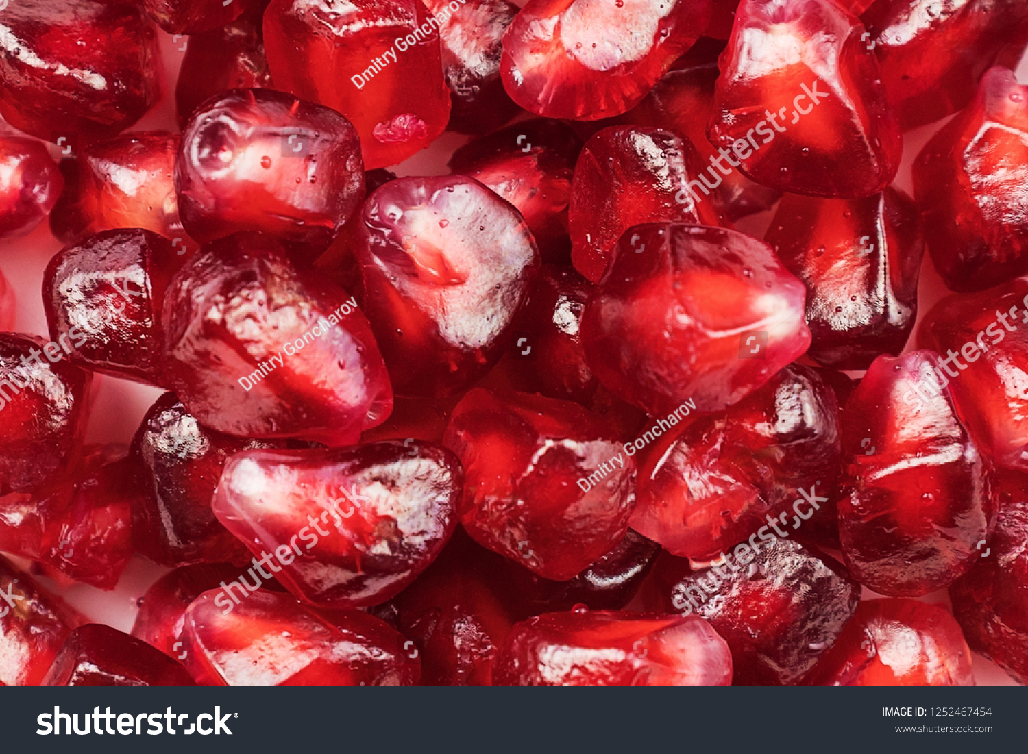 Red juicy pomegranate seeds form the background texture. Close-up #1252467454