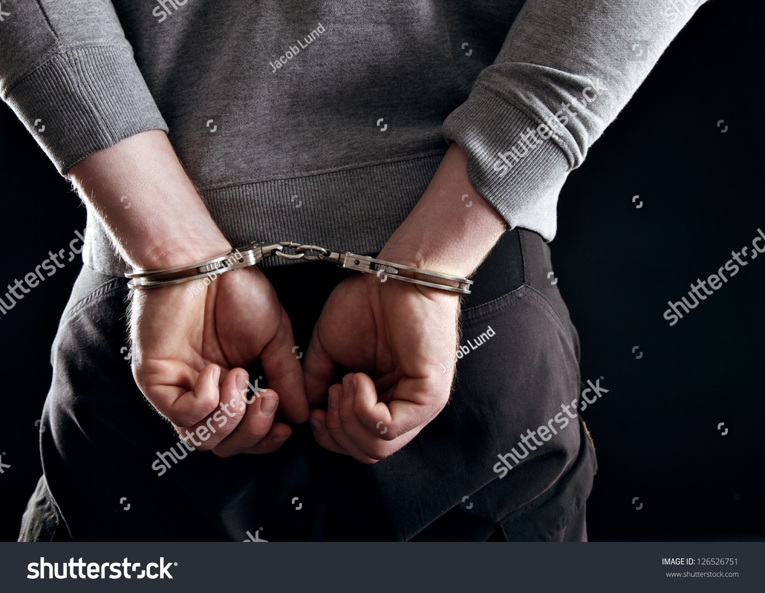 Outlaw's hands locked in handcuffs isolated on black #126526751