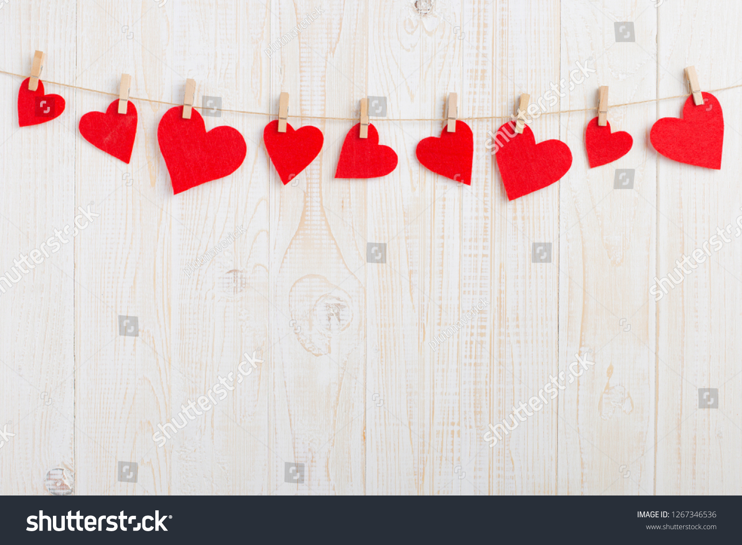 Red hearts on rope with clothespins, on a white wooden background. Place for text, copy space. #1267346536